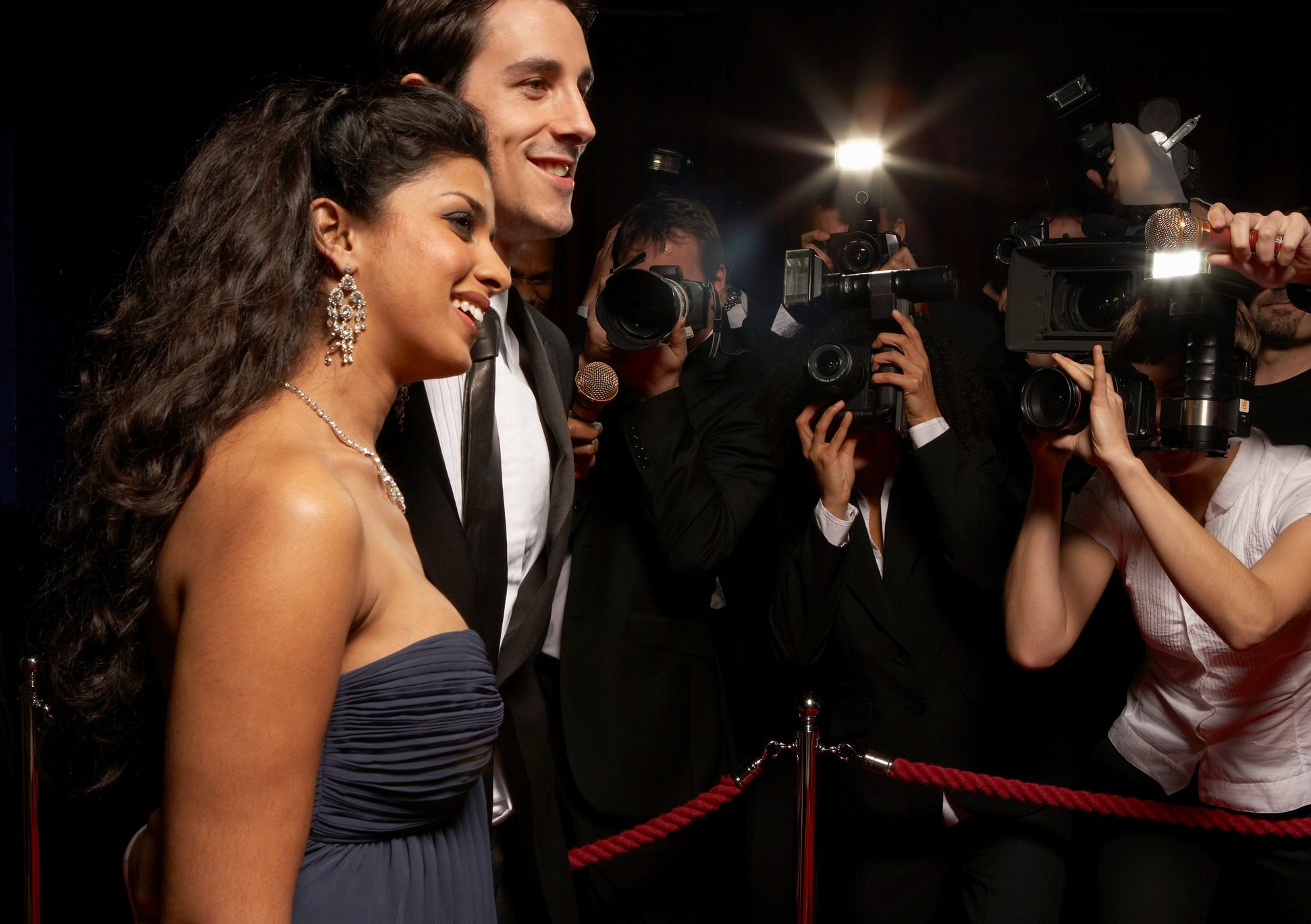 Paparazzi photographing celebrity couple in evening wear at event